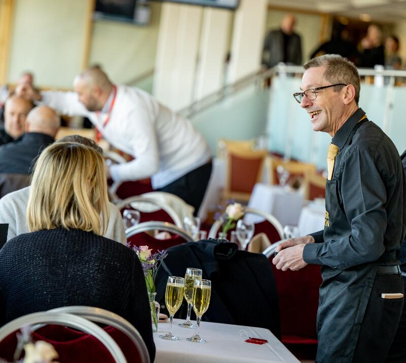 A couple being served by a waiter in Lingfield Racecourse hospitality