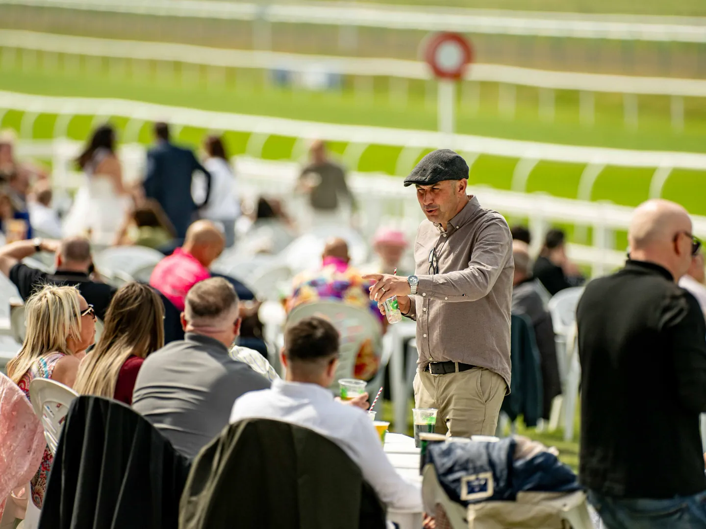 Man in a flat cap among spectators at Lingfield Park