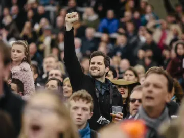 A man in the crowd at Lingfield Races punches the air in celebration
