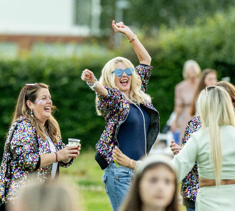 A group of ladies in sparkly jackets laughing and dancing at Lingfield Park