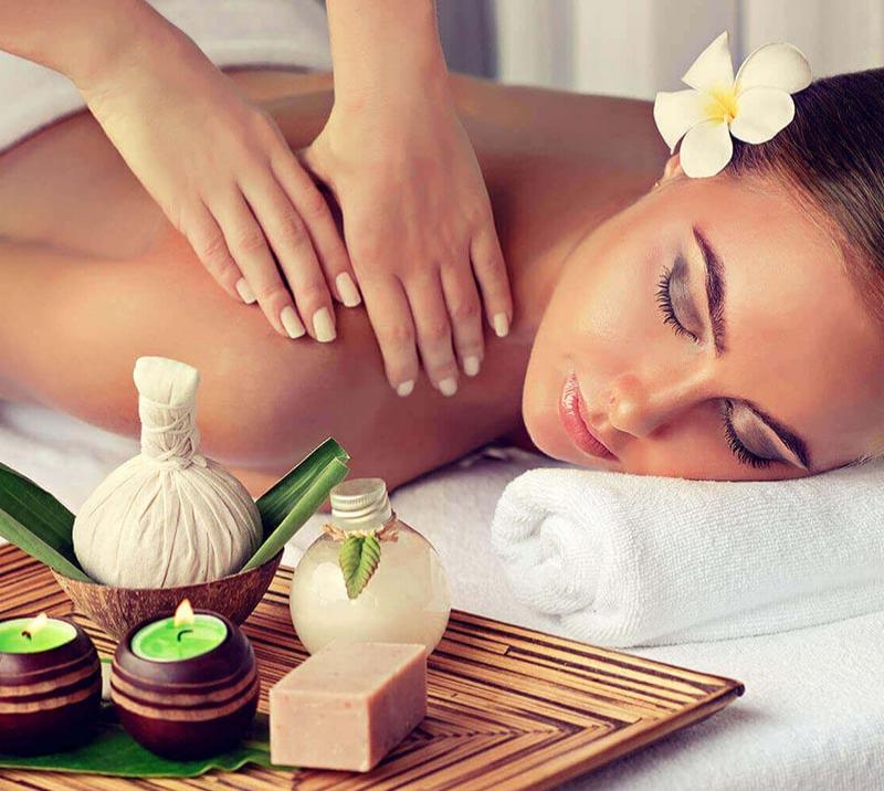 A lady relaxes on fresh white towels while enjoying a shoulder massage.