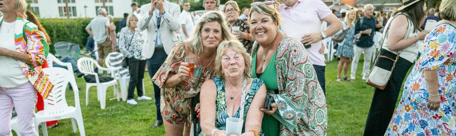 A small group of ladies dressed for the races in the summer pose for a picture at Lingfield