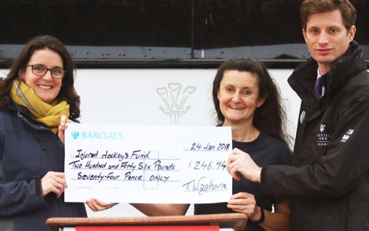A cheque held by three people, written for a charity to receive.