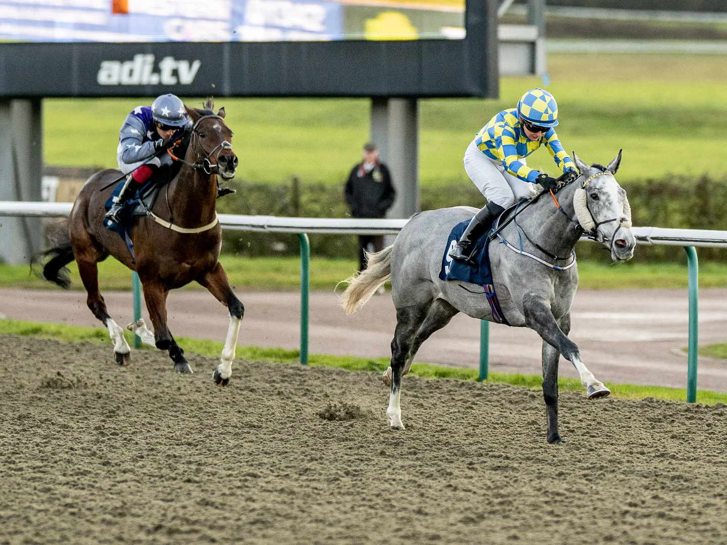 Two horses and jockeys battling for position on the All Weather track at Lingfield Park