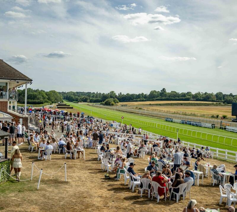 The crowds sitting out in front of the grandstands at Lingfield Park Races