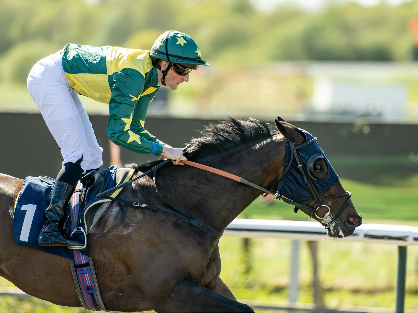 Jockeys in light blue silks on the All Weather track at Lingfield Park on a sunny afternoon