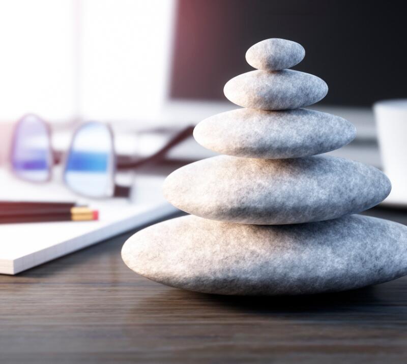 wellness stones on desk with coffee cup, glasses, notebook and pens