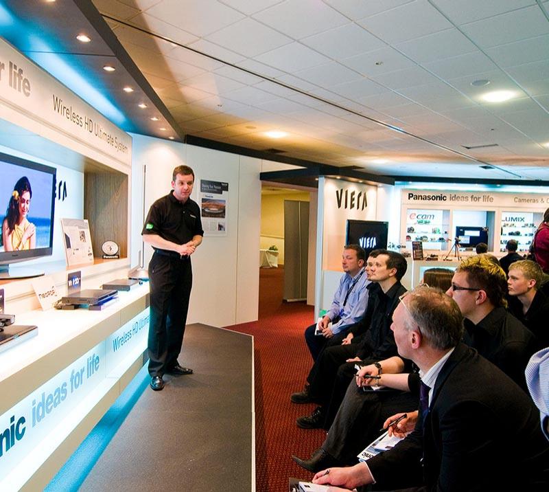 A standing speaker discusses the days topic with a small seated audience