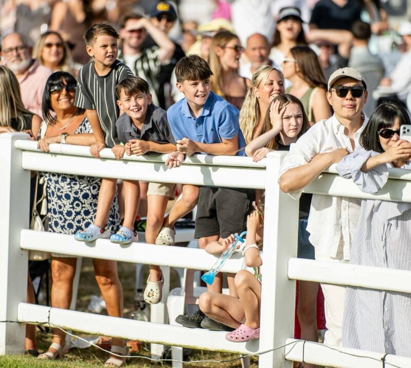 Race goers watching on from the fences at the trackside at Lingfield Park